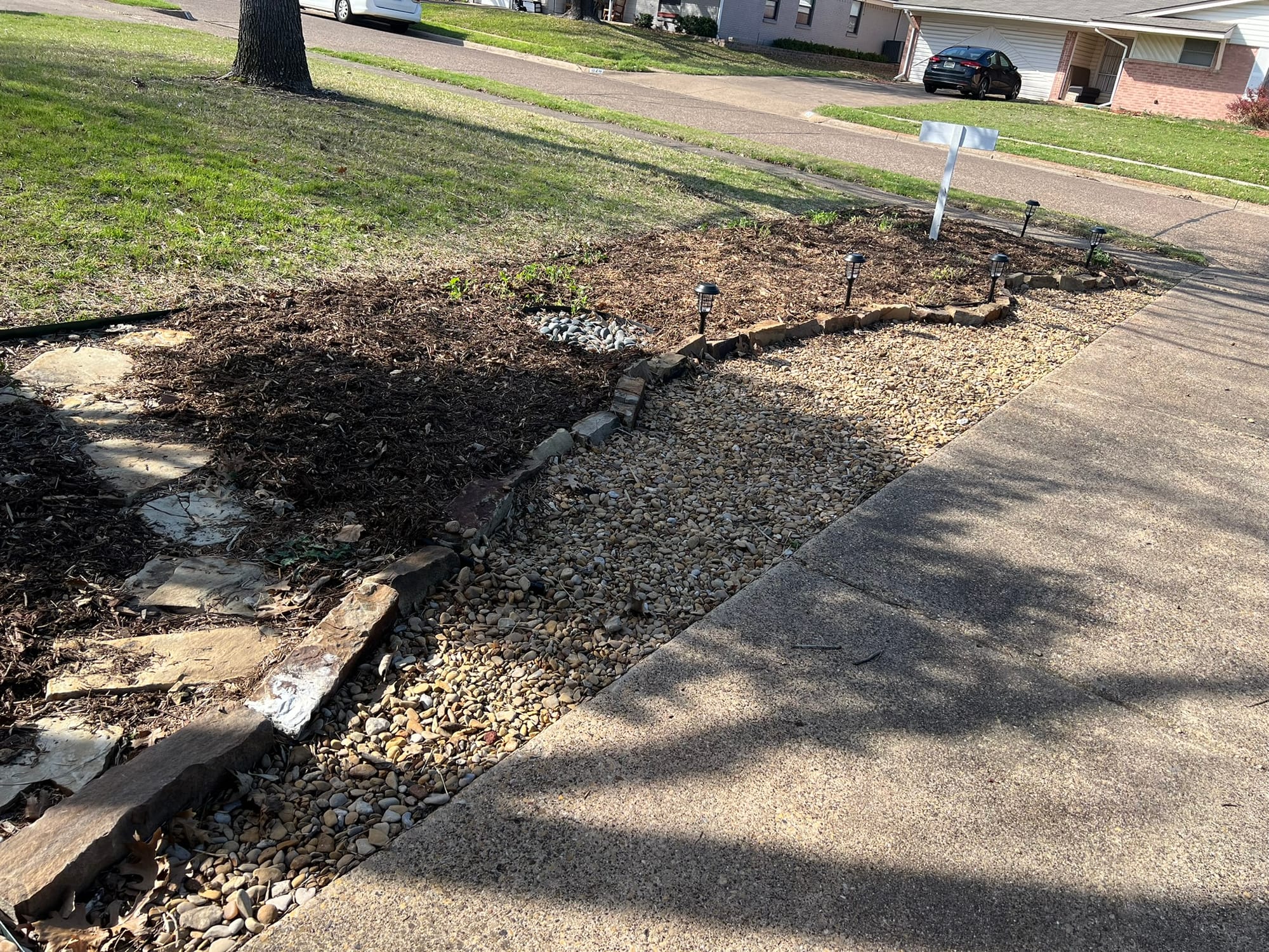 Freshly maintained garden bed with mulch, rocks and stepping stones requiring regular upkeep