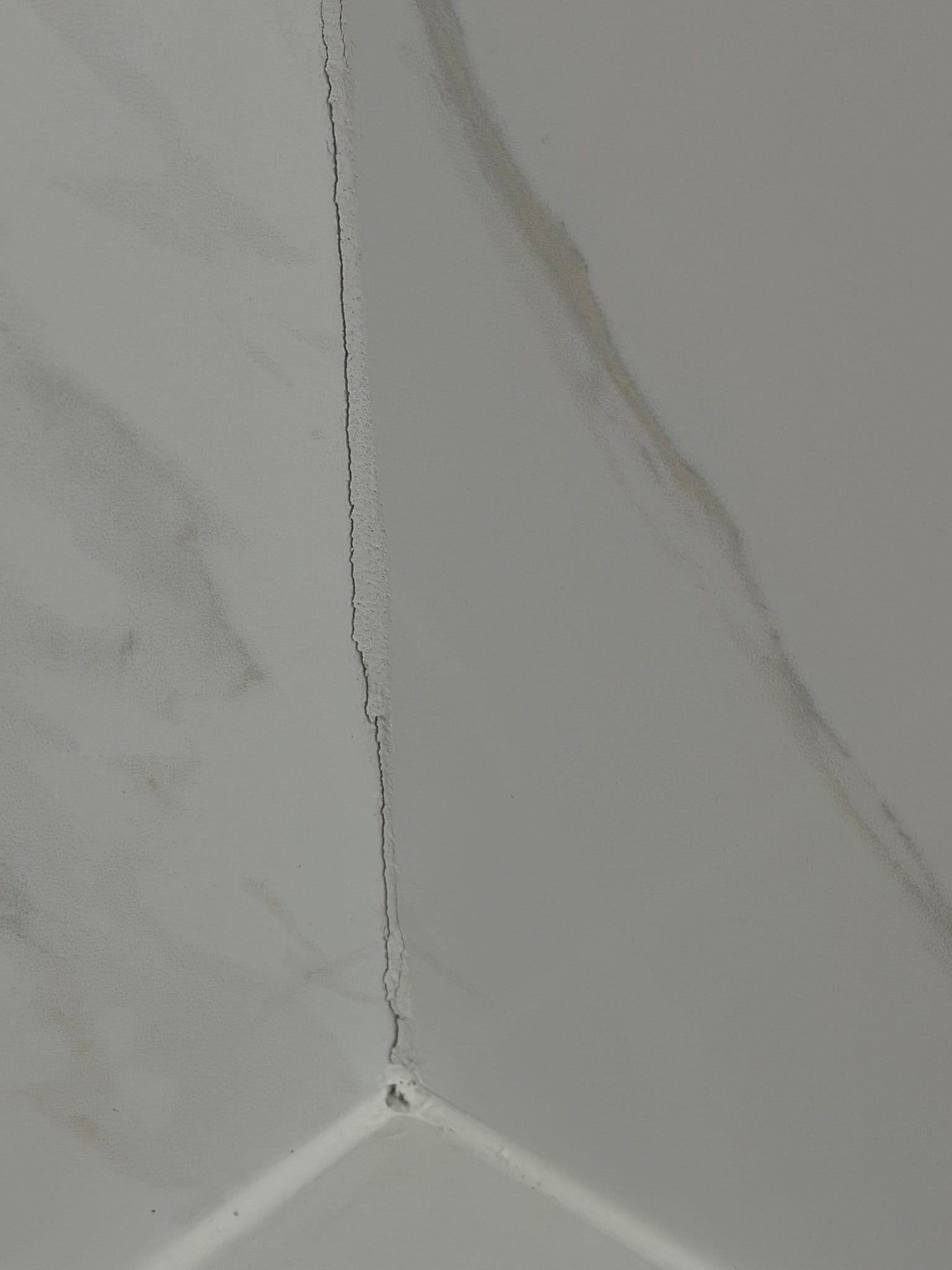 Close-up of cracked grout in shower showing damage from transportation vibration